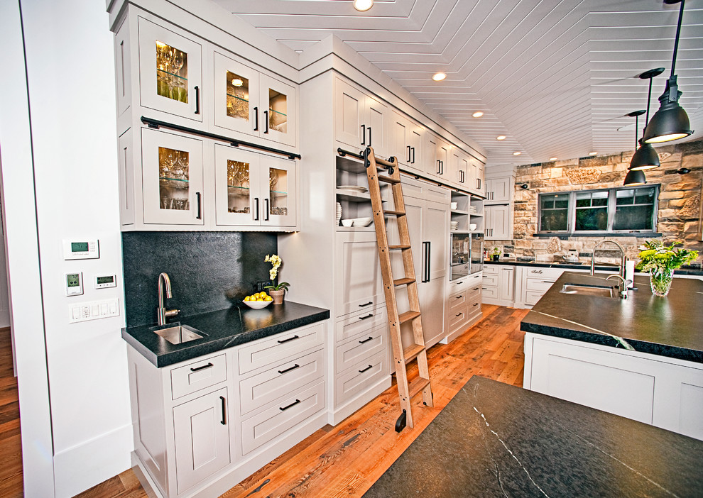Inspiration for a large rustic l-shaped medium tone wood floor and brown floor eat-in kitchen remodel with an undermount sink, shaker cabinets, gray cabinets, soapstone countertops, black backsplash, stone slab backsplash, stainless steel appliances and two islands