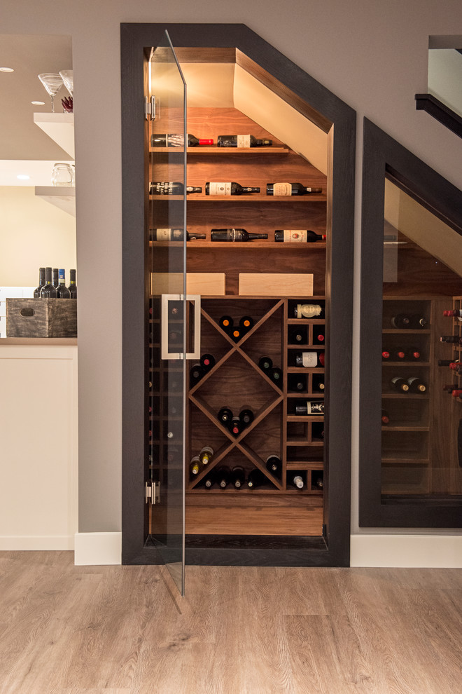 This is an example of a small contemporary wine cellar in Calgary with light hardwood floors and display racks.