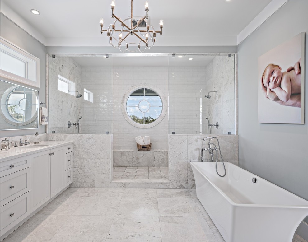 Large beach style master bathroom in Miami with shaker cabinets, white cabinets, a freestanding tub, a double shower, a one-piece toilet, white tile, subway tile, blue walls, marble floors, an undermount sink, marble benchtops, white floor and an open shower.