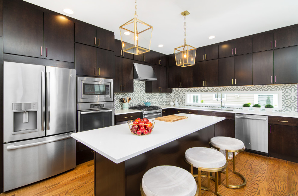Photo of a mid-sized contemporary l-shaped open plan kitchen in Detroit with an undermount sink, flat-panel cabinets, dark wood cabinets, quartz benchtops, blue splashback, porcelain splashback, stainless steel appliances, light hardwood floors, with island, brown floor and white benchtop.