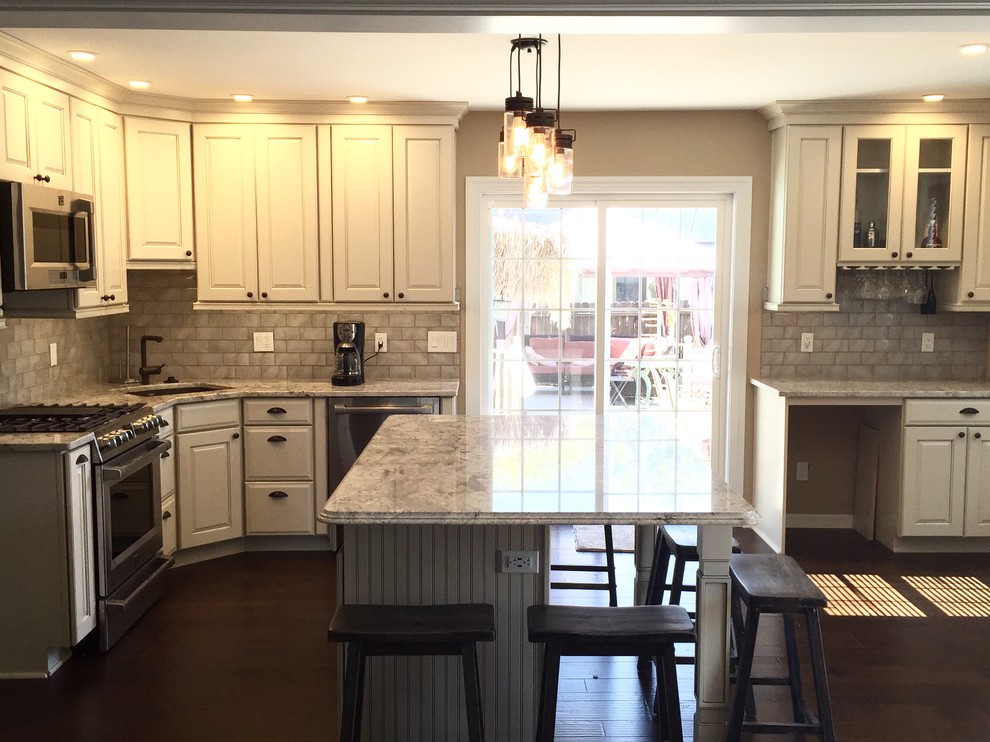 Example of a large transitional u-shaped dark wood floor eat-in kitchen design in Atlanta with an undermount sink, raised-panel cabinets, beige cabinets, granite countertops, beige backsplash, glass tile backsplash, stainless steel appliances and an island