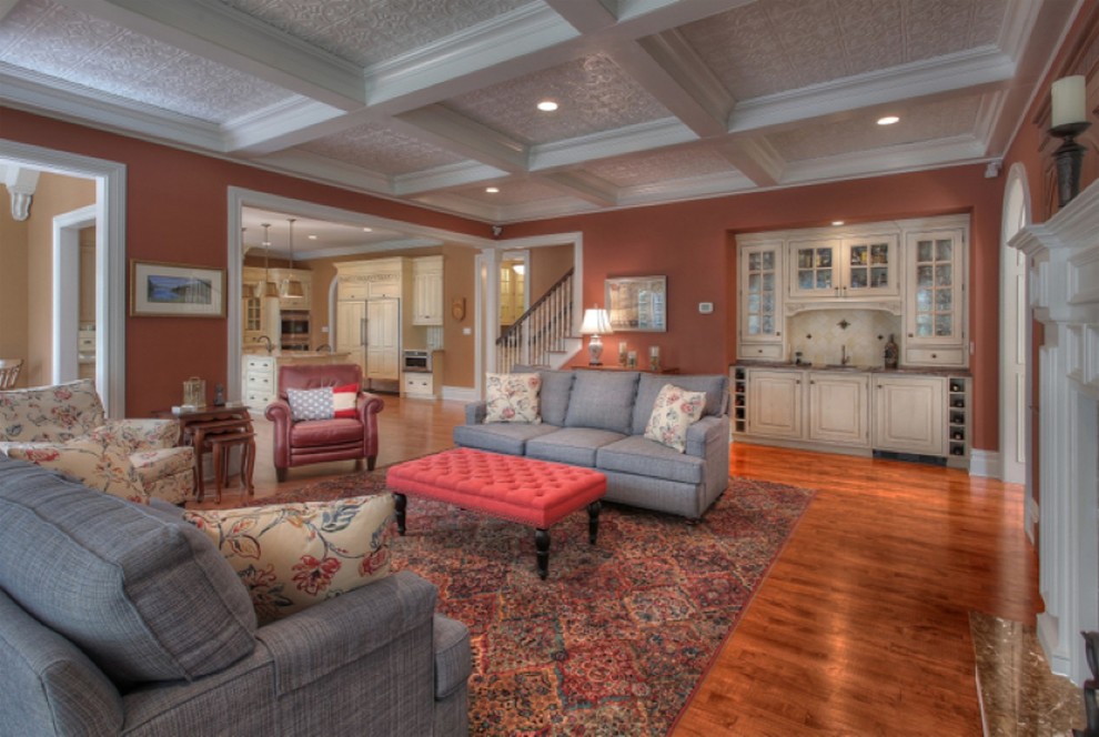 This is an example of a large traditional open concept family room in New York with red walls, medium hardwood floors, a built-in media wall, a home bar and brown floor.