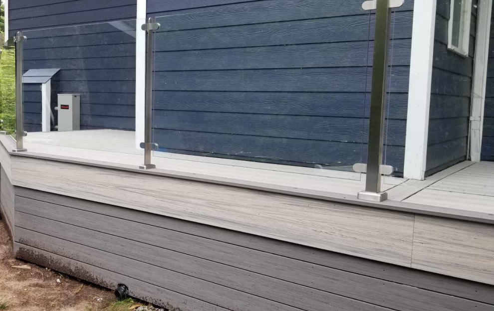 Photo of an expansive backyard deck in Toronto with with skirting and glass railing.