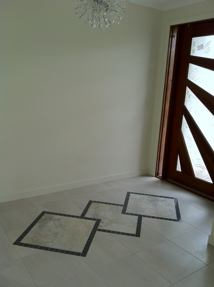Photo of a contemporary entryway in Brisbane with porcelain floors, a pivot front door and a dark wood front door.