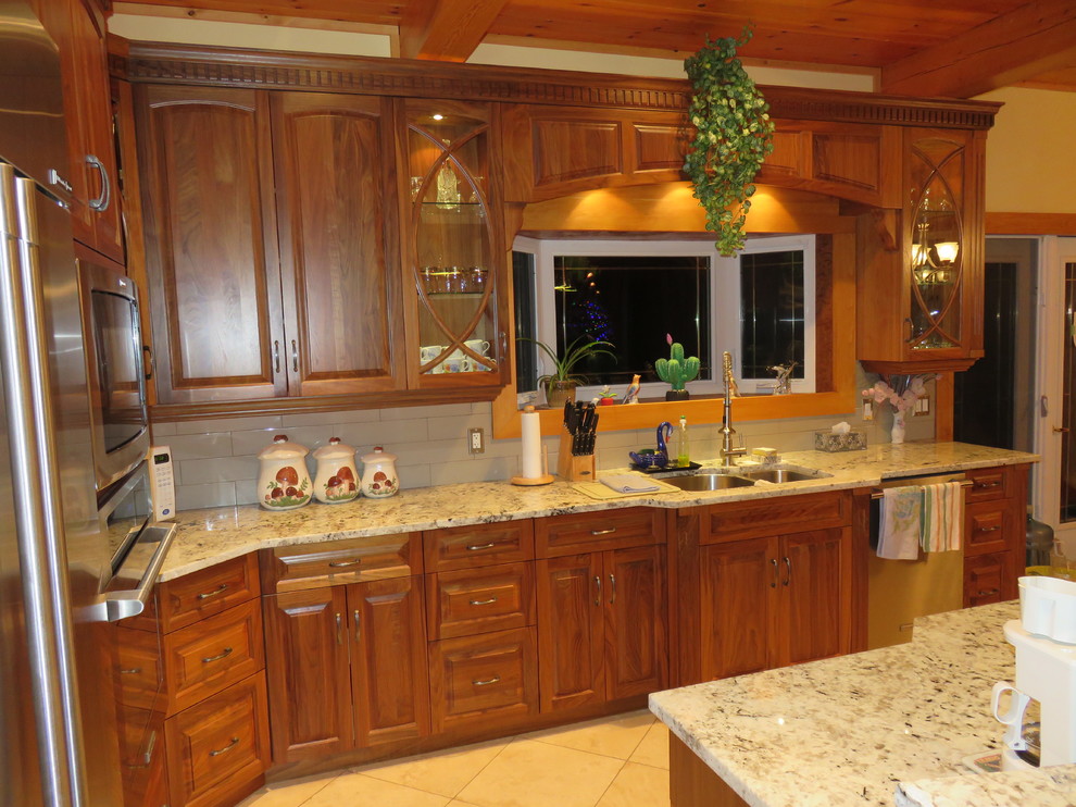 Open concept kitchen - large transitional l-shaped ceramic tile open concept kitchen idea with raised-panel cabinets, medium tone wood cabinets, granite countertops, stainless steel appliances, an island, a double-bowl sink, white backsplash and subway tile backsplash