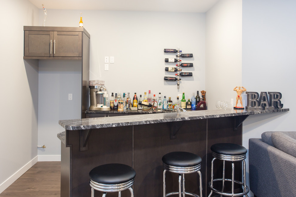 Design ideas for a mid-sized modern galley seated home bar in Calgary with an undermount sink, shaker cabinets, medium wood cabinets, granite benchtops, brown splashback and vinyl floors.