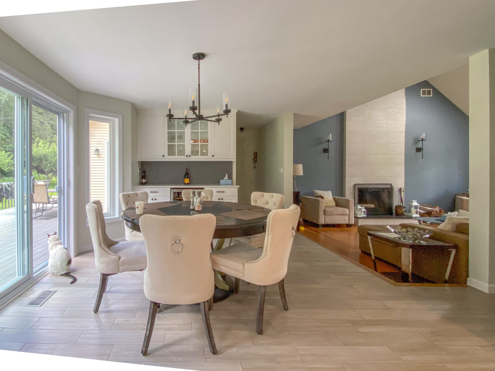 This is an example of an expansive contemporary open plan dining room in Bridgeport with grey walls, porcelain flooring, a standard fireplace, a tiled fireplace surround, grey floors and a vaulted ceiling.