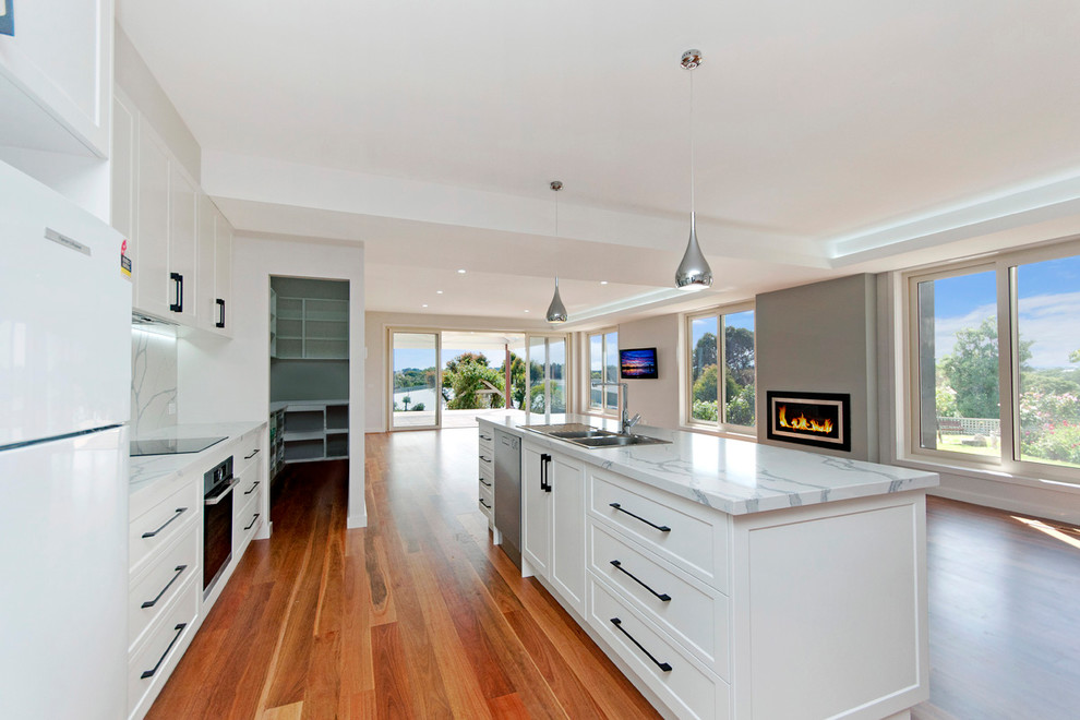 This is an example of a transitional open plan kitchen in Other with a double-bowl sink, marble benchtops, white splashback, marble splashback, stainless steel appliances, medium hardwood floors and with island.