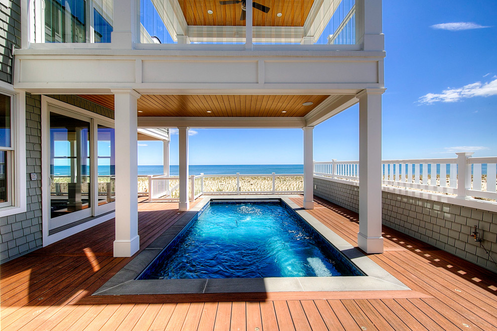 This is an example of a beach style side yard rectangular aboveground pool in New York with with privacy feature and decking.