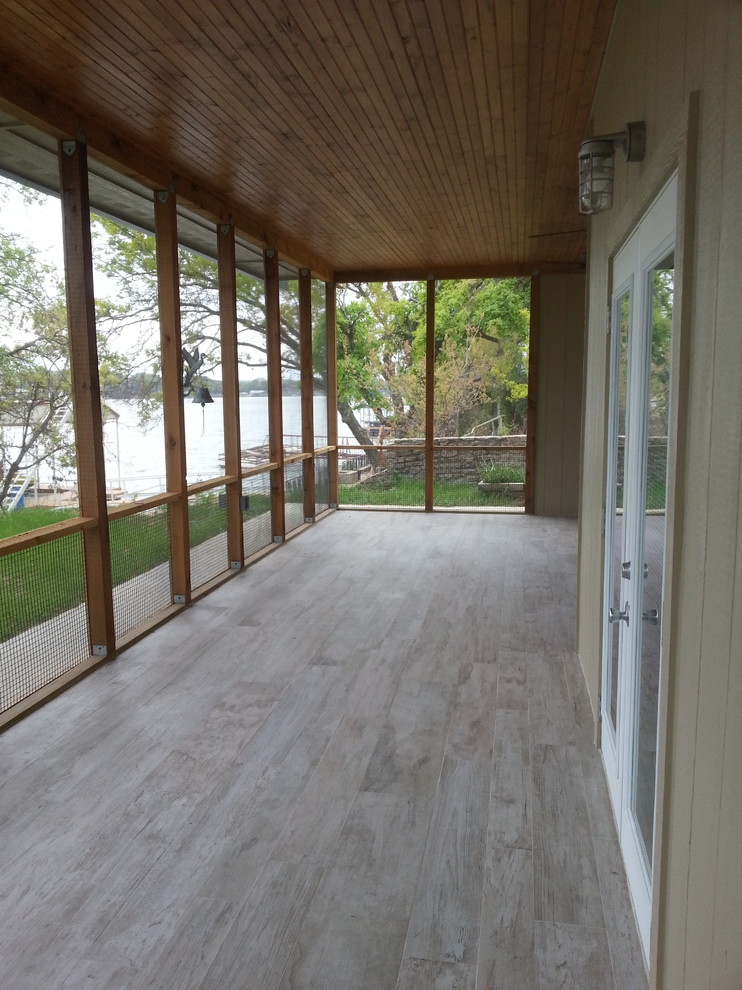 This is an example of a large contemporary backyard screened-in verandah in Dallas with a roof extension.