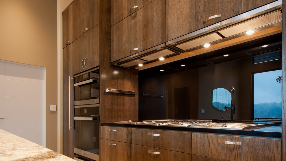 Mid-sized contemporary galley eat-in kitchen in Seattle with flat-panel cabinets, medium wood cabinets, quartz benchtops, black splashback, glass sheet splashback, stainless steel appliances, concrete floors, with island and an undermount sink.