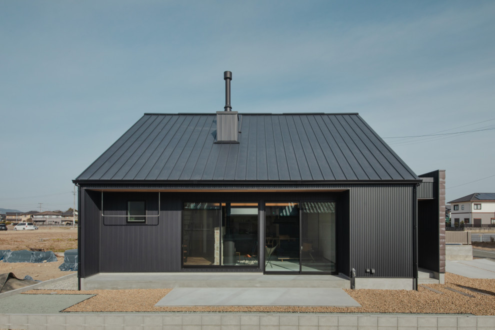 Inspiration för ett funkis svart hus, med två våningar, sadeltak och tak i metall