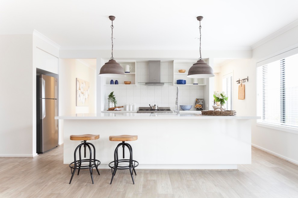 Inspiration for a mid-sized transitional galley kitchen in Melbourne with white splashback, ceramic splashback, light hardwood floors, with island, brown floor, white benchtop, an undermount sink, open cabinets, white cabinets and stainless steel appliances.