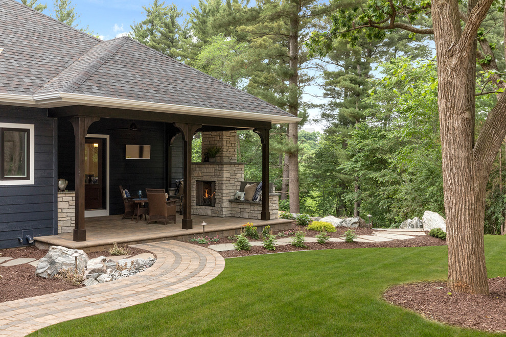 Mid-sized transitional backyard patio in Other with with fireplace, brick pavers and a roof extension.