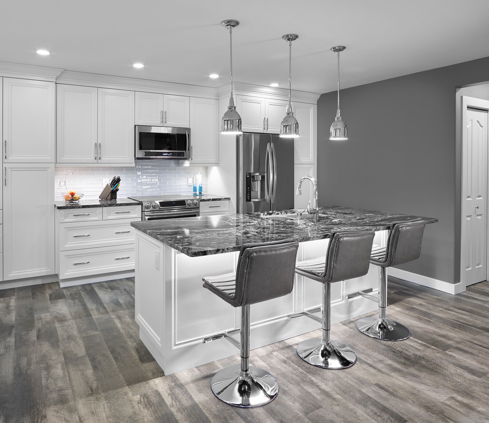 Mid-sized transitional galley vinyl floor eat-in kitchen photo in Edmonton with an undermount sink, recessed-panel cabinets, white cabinets, granite countertops, white backsplash, subway tile backsplash, stainless steel appliances and an island