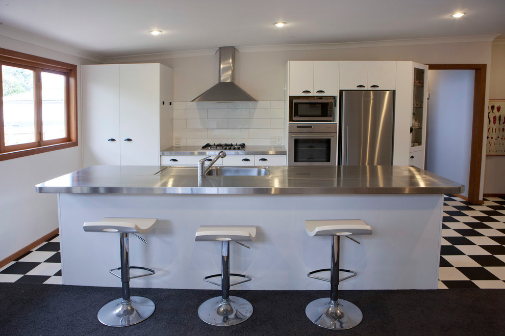 This is an example of a traditional eat-in kitchen in Wellington with an integrated sink, stainless steel benchtops, stainless steel appliances and with island.