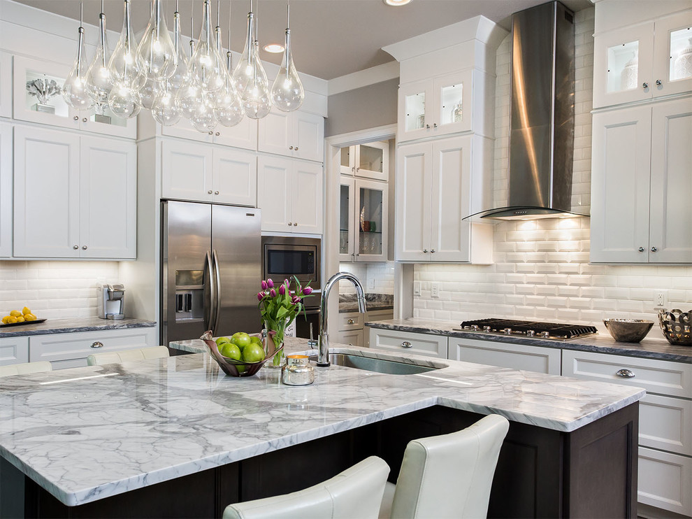 Example of a mid-sized transitional single-wall dark wood floor and brown floor eat-in kitchen design in Columbus with an undermount sink, recessed-panel cabinets, white cabinets, granite countertops, white backsplash, subway tile backsplash, stainless steel appliances and an island