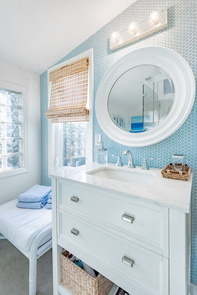 Inspiration for a beach style bathroom in Charleston with recessed-panel cabinets, white cabinets, blue tile, mosaic tile, white walls, an undermount sink, grey floor and white benchtops.