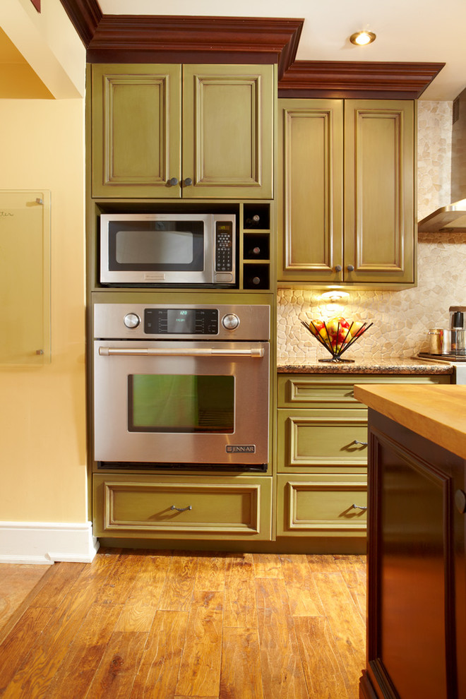 Kitchen - mid-sized transitional light wood floor kitchen idea in Toronto with an undermount sink, green cabinets, granite countertops, beige backsplash, stone tile backsplash, stainless steel appliances and an island