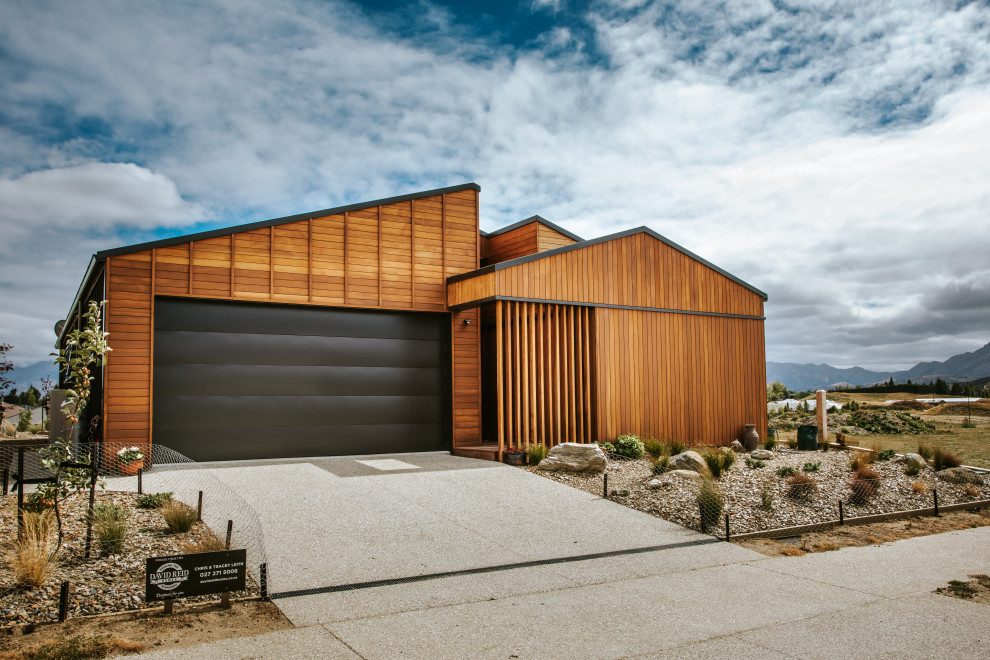 Ejemplo de fachada de casa marrón y negra retro de tamaño medio de una planta con revestimiento de madera, tejado plano, tejado de metal y panel y listón