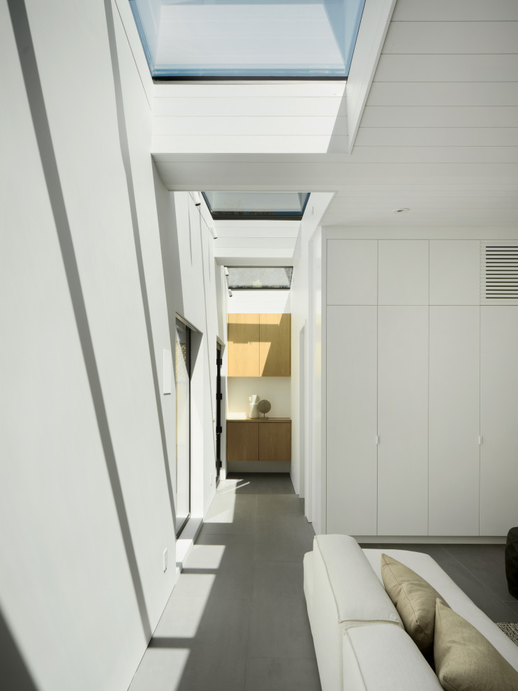 Large minimalist porcelain tile, gray floor and vaulted ceiling hallway photo in San Francisco with white walls
