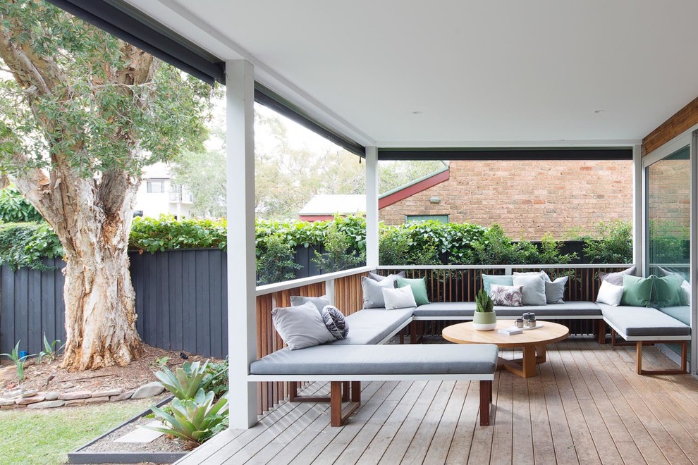 Photo of a large contemporary backyard deck in Sydney with a roof extension.