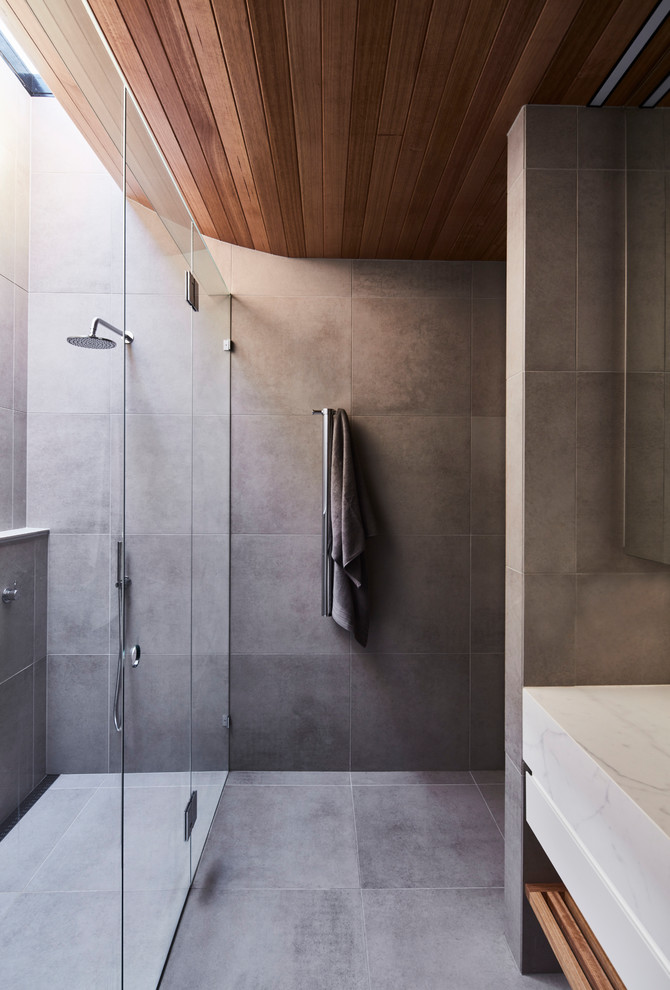 Design ideas for a mid-sized contemporary master bathroom in Melbourne with flat-panel cabinets, white cabinets, a double shower, a wall-mount toilet, gray tile, porcelain tile, grey walls, porcelain floors, an undermount sink, marble benchtops, grey floor, a hinged shower door and white benchtops.
