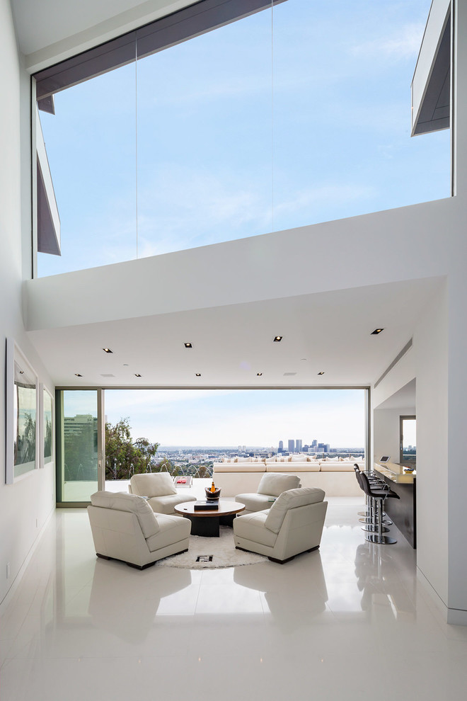 This is an example of a contemporary living room in Los Angeles with a home bar, white walls and concrete floors.