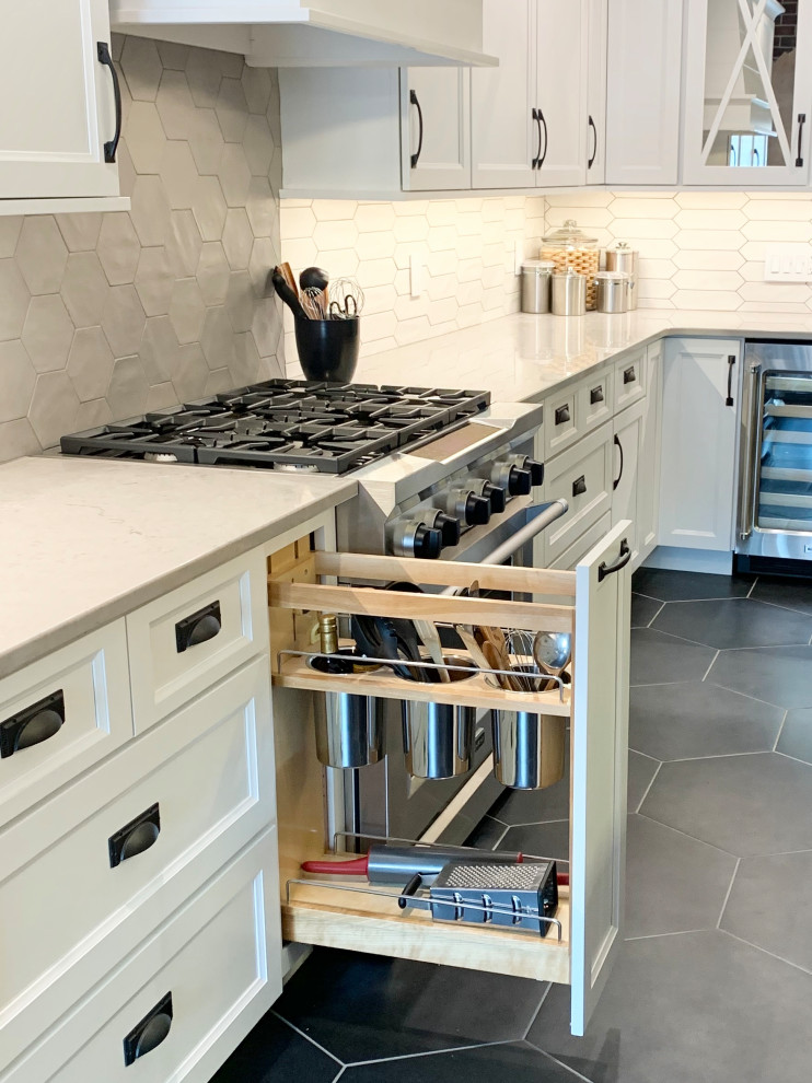 This is an example of a large transitional l-shaped eat-in kitchen in Other with a farmhouse sink, recessed-panel cabinets, white cabinets, quartz benchtops, multi-coloured splashback, ceramic splashback, stainless steel appliances, ceramic floors, with island, black floor and white benchtop.