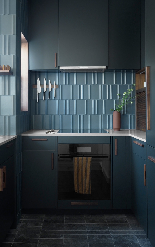 Modelo de cocina comedor minimalista pequeña con península, puertas de armario azules, encimera de cemento, salpicadero azul, salpicadero de azulejos de cerámica, electrodomésticos negros y suelo azul