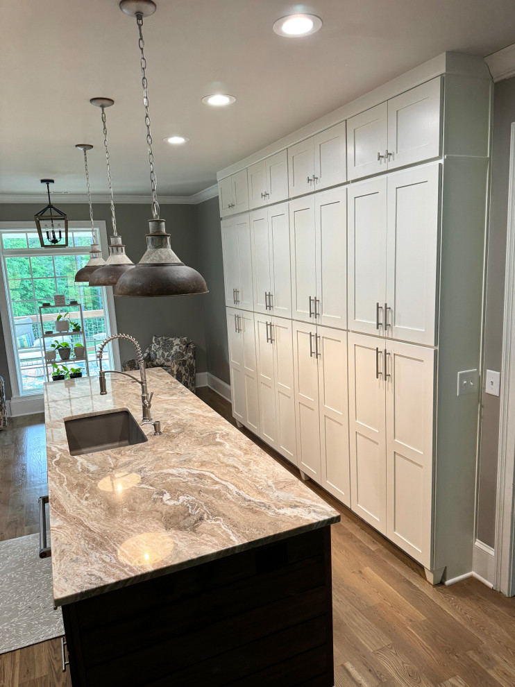 Transitional galley medium tone wood floor and brown floor eat-in kitchen photo in Atlanta with an undermount sink, shaker cabinets, white cabinets, granite countertops, gray backsplash, ceramic backsplash, stainless steel appliances, an island and multicolored countertops