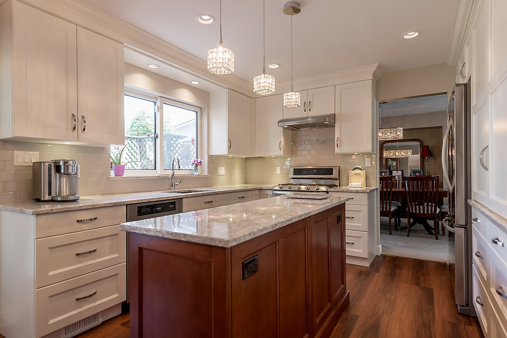 Inspiration for a mid-sized transitional separate kitchen in Vancouver with an undermount sink, recessed-panel cabinets, white cabinets, quartz benchtops, grey splashback, subway tile splashback, stainless steel appliances, vinyl floors and with island.
