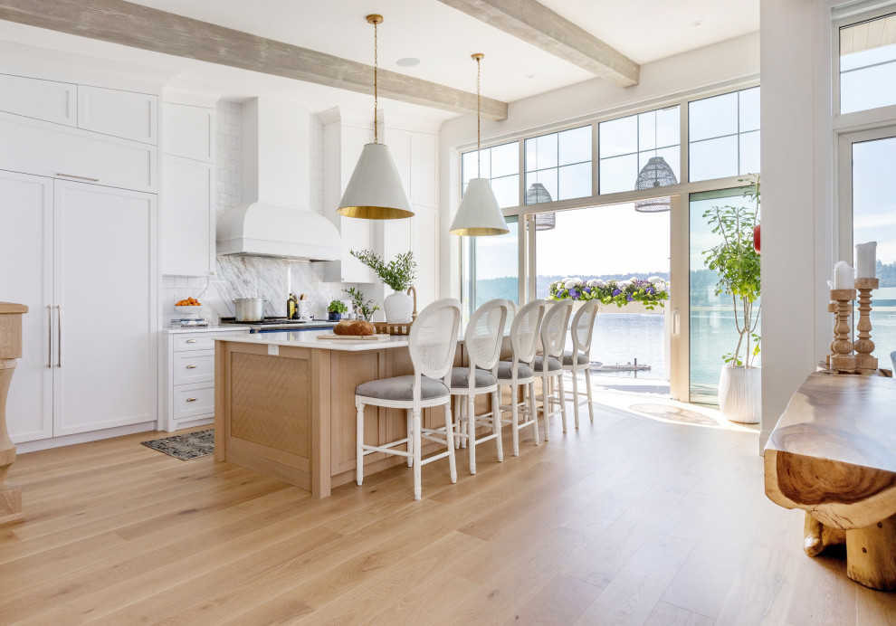 This is an example of a beach style single-wall kitchen in Vancouver with a farmhouse sink, shaker cabinets, light hardwood floors, with island, beige floor and exposed beam.