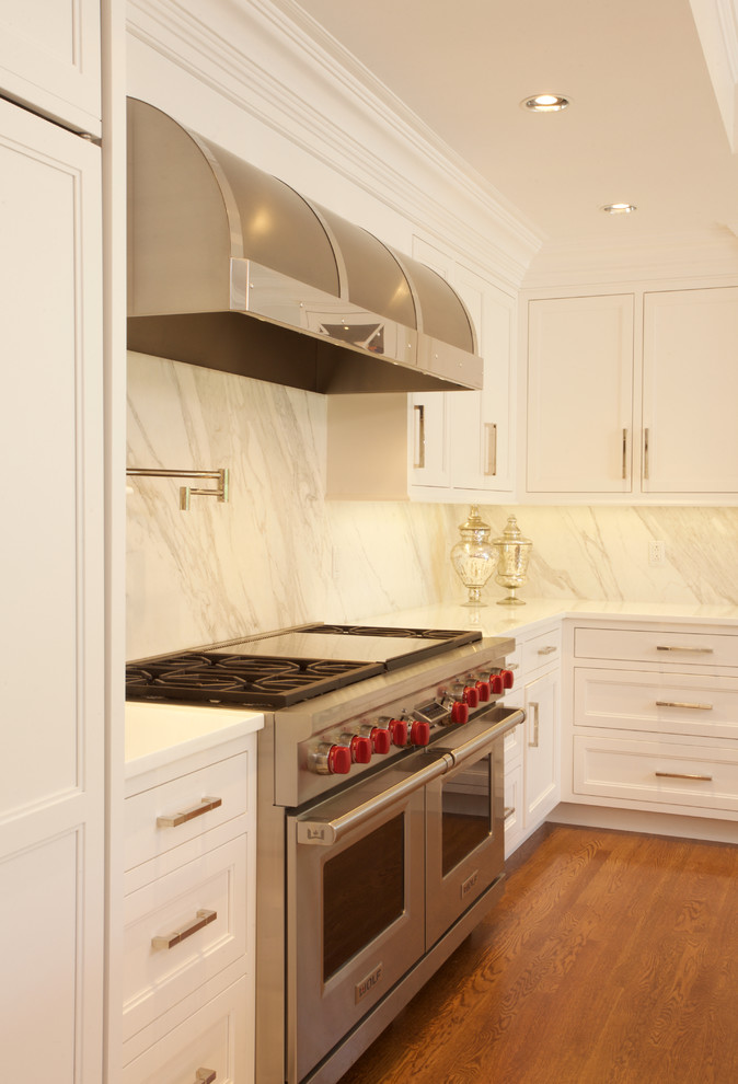 Example of a large transitional u-shaped medium tone wood floor eat-in kitchen design in New York with white cabinets, marble countertops, stone slab backsplash, paneled appliances, an island, an undermount sink and recessed-panel cabinets