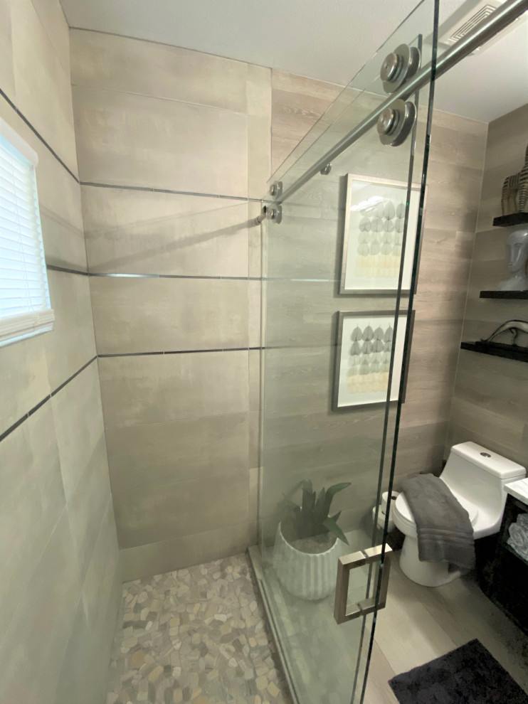 Photo of a mid-sized modern 3/4 bathroom in Austin with a double shower, ceramic tile, a vessel sink, a sliding shower screen, flat-panel cabinets, black cabinets, gray tile, light hardwood floors, granite benchtops, beige floor and grey benchtops.
