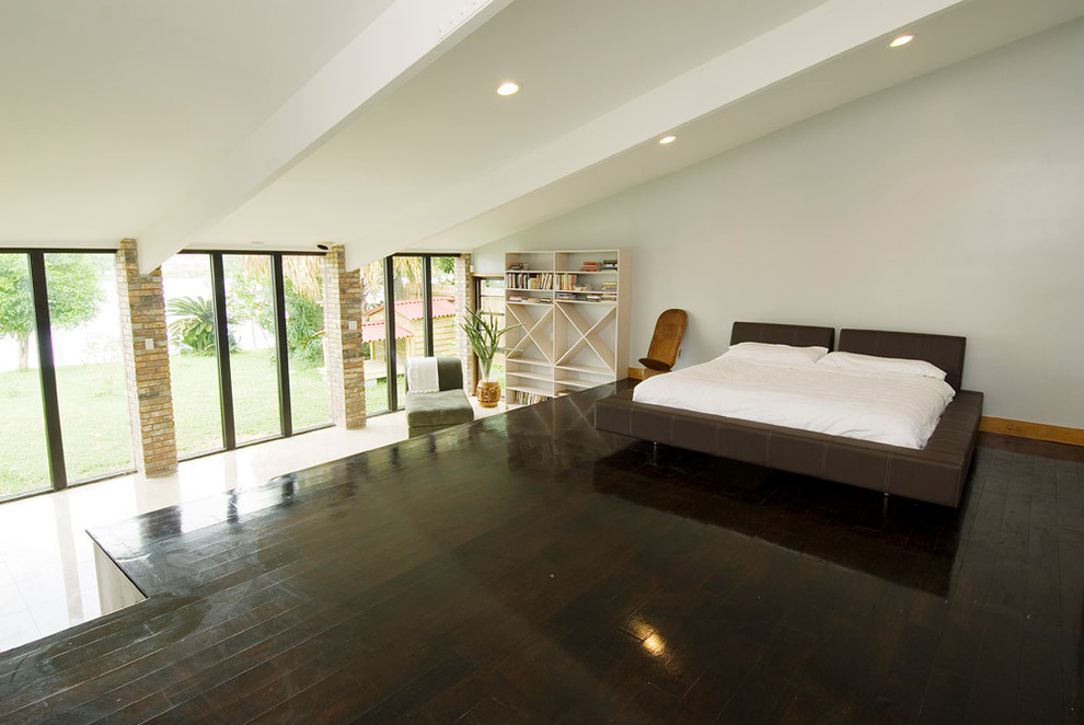 This is an example of a contemporary loft-style bedroom in New Orleans with white walls and dark hardwood floors.