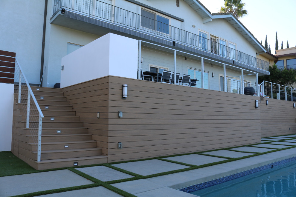 Photo of an expansive contemporary backyard and ground level deck in Los Angeles with with dock, no cover and cable railing.