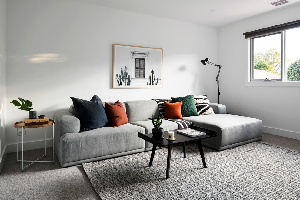 Photo of a contemporary enclosed living room in Melbourne with white walls, carpet, a freestanding tv and grey floor.