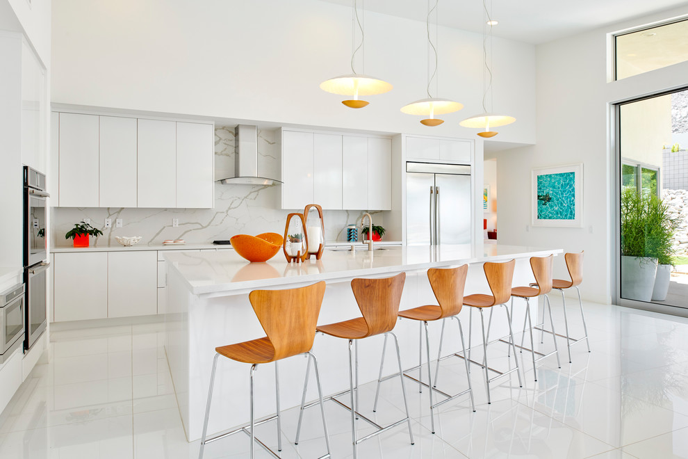Midcentury kitchen in Orange County with flat-panel cabinets, white cabinets, marble benchtops, white splashback, marble splashback, stainless steel appliances, with island, white floor and white benchtop.