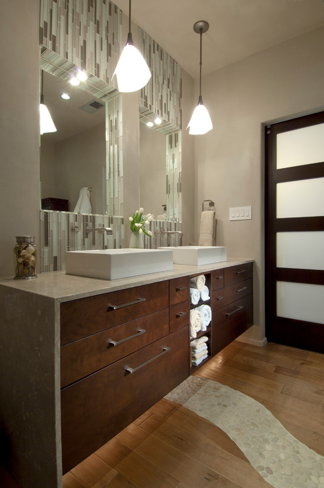 Inspiration for a contemporary bathroom in San Diego with flat-panel cabinets, dark wood cabinets, a freestanding tub, brown tile, gray tile, green tile, matchstick tile, beige walls, light hardwood floors, a vessel sink and soapstone benchtops.