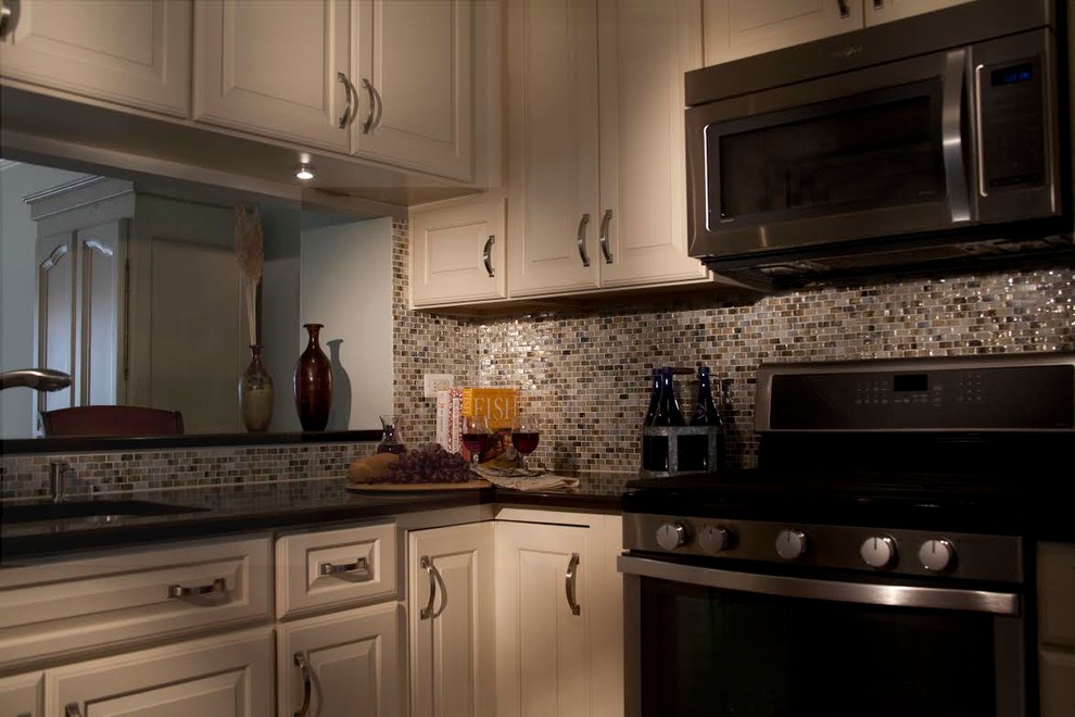 Small transitional l-shaped light wood floor eat-in kitchen photo in Chicago with a double-bowl sink, raised-panel cabinets, white cabinets, solid surface countertops, multicolored backsplash, stone tile backsplash and stainless steel appliances