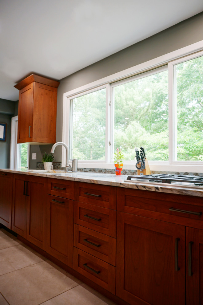 Eat-in kitchen - mid-sized transitional porcelain tile and gray floor eat-in kitchen idea with recessed-panel cabinets, medium tone wood cabinets, quartzite countertops, green backsplash, mosaic tile backsplash, stainless steel appliances and an island