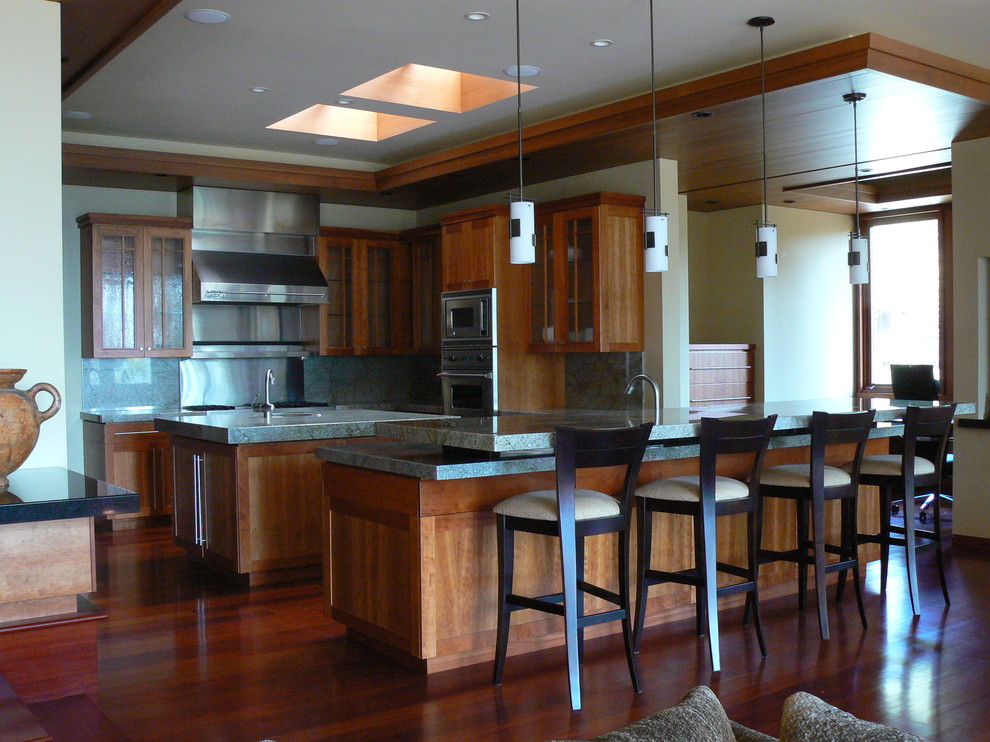 Photo of a large contemporary u-shaped separate kitchen in San Diego with glass-front cabinets, medium wood cabinets, granite benchtops, grey splashback, stone tile splashback, stainless steel appliances, dark hardwood floors, with island and an undermount sink.