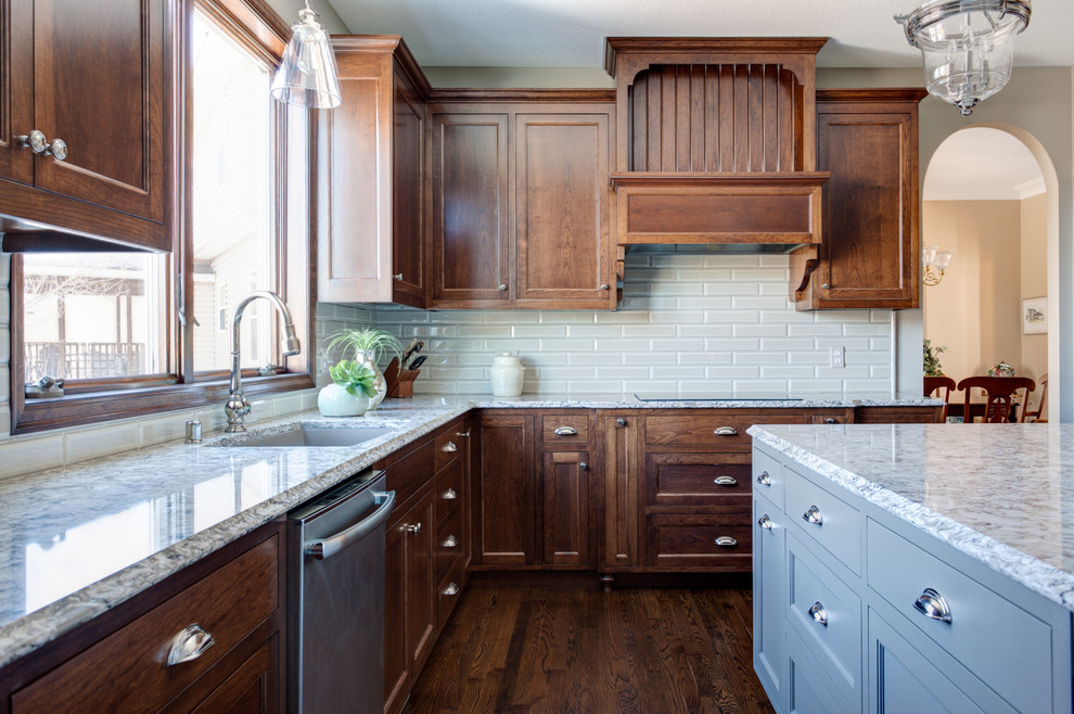 Design ideas for a large traditional l-shaped eat-in kitchen in Minneapolis with an undermount sink, beaded inset cabinets, dark wood cabinets, granite benchtops, green splashback, subway tile splashback, stainless steel appliances, dark hardwood floors and with island.