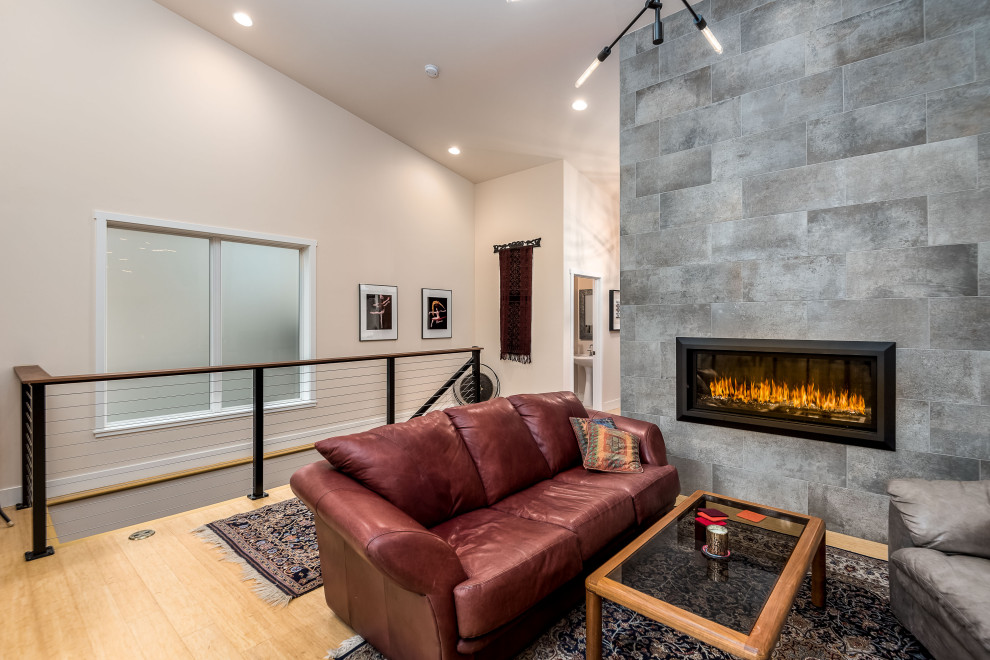 This is an example of a large midcentury open concept living room in Portland with white walls, light hardwood floors, a hanging fireplace, a tile fireplace surround and brown floor.