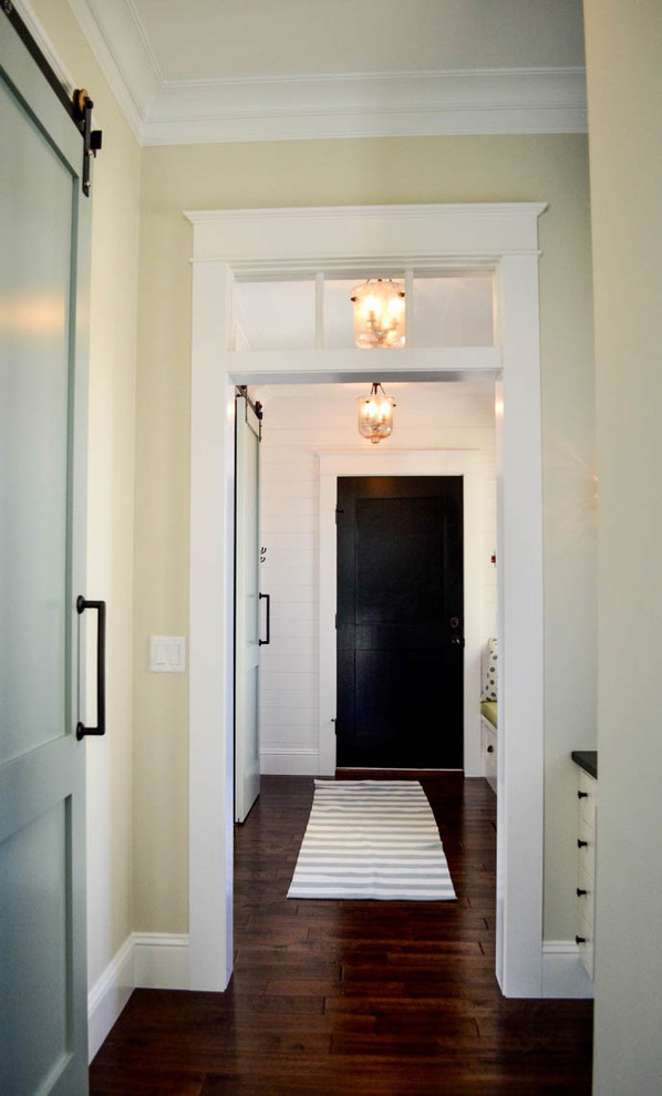 Transitional dark wood floor mudroom photo with white walls and a black front door
