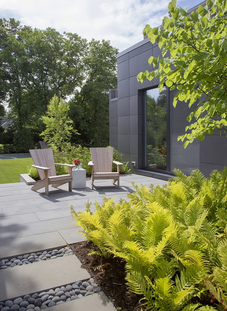 Large modern side yard patio in Boston with natural stone pavers and no cover.