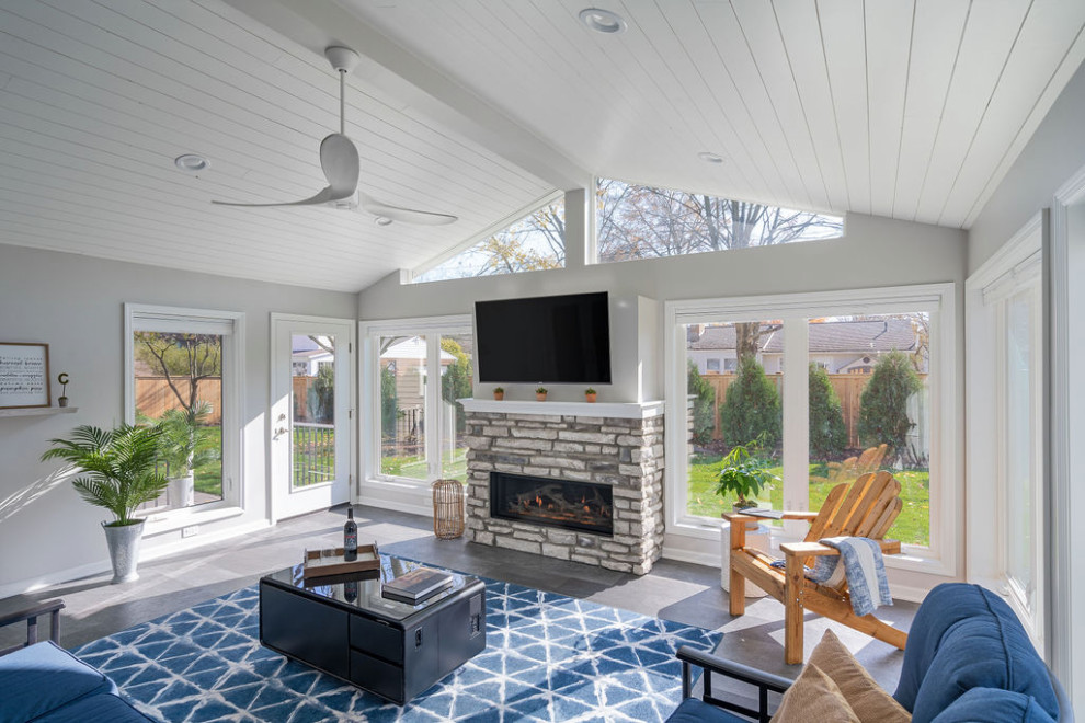 This is an example of a large traditional conservatory in Columbus with vinyl flooring, a standard fireplace, a stone fireplace surround and grey floors.