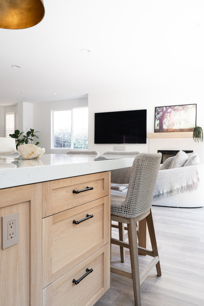 Inspiration for a large beach style u-shaped open plan kitchen in Denver with an undermount sink, recessed-panel cabinets, light wood cabinets, quartz benchtops, white splashback, ceramic splashback, stainless steel appliances, vinyl floors, with island, beige floor and white benchtop.