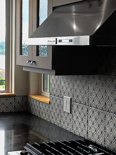 Example of a large eclectic u-shaped laminate floor and brown floor eat-in kitchen design with an undermount sink, glass-front cabinets, gray cabinets, quartz countertops, multicolored backsplash, ceramic backsplash, stainless steel appliances, an island and black countertops
